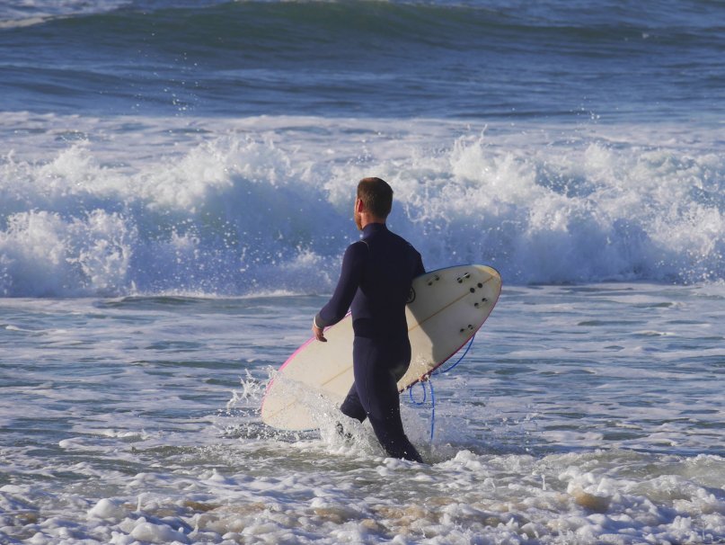 surfeur entrant dans les vagues sur une plage de Mimizan