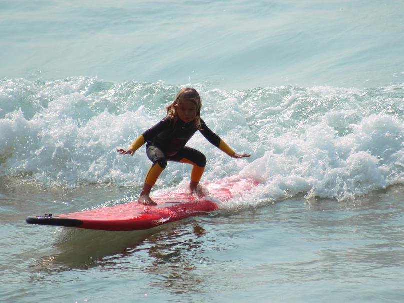 enfant debout sur une planche de surf en mousse dans les Landes